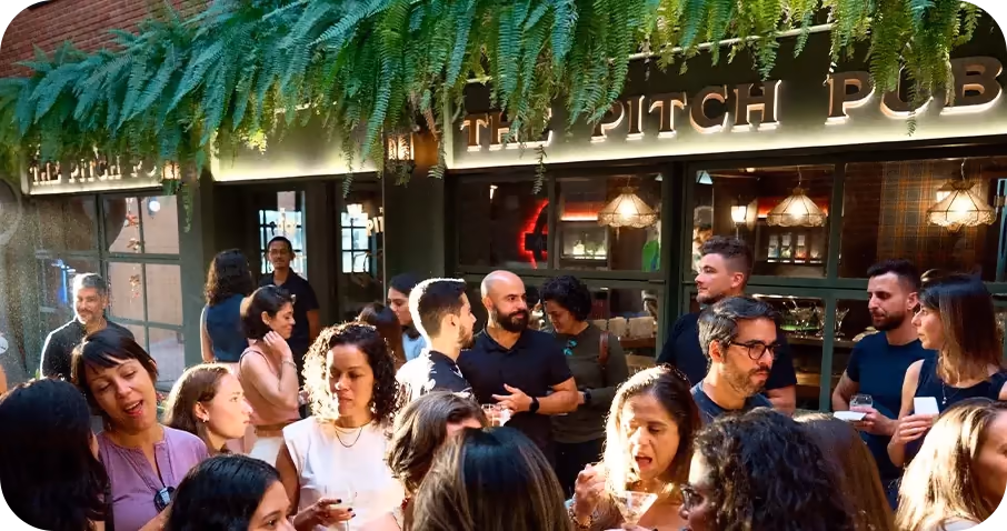 Pessoas conversando em um encontro na Softown, diante do The Pitch Pub.