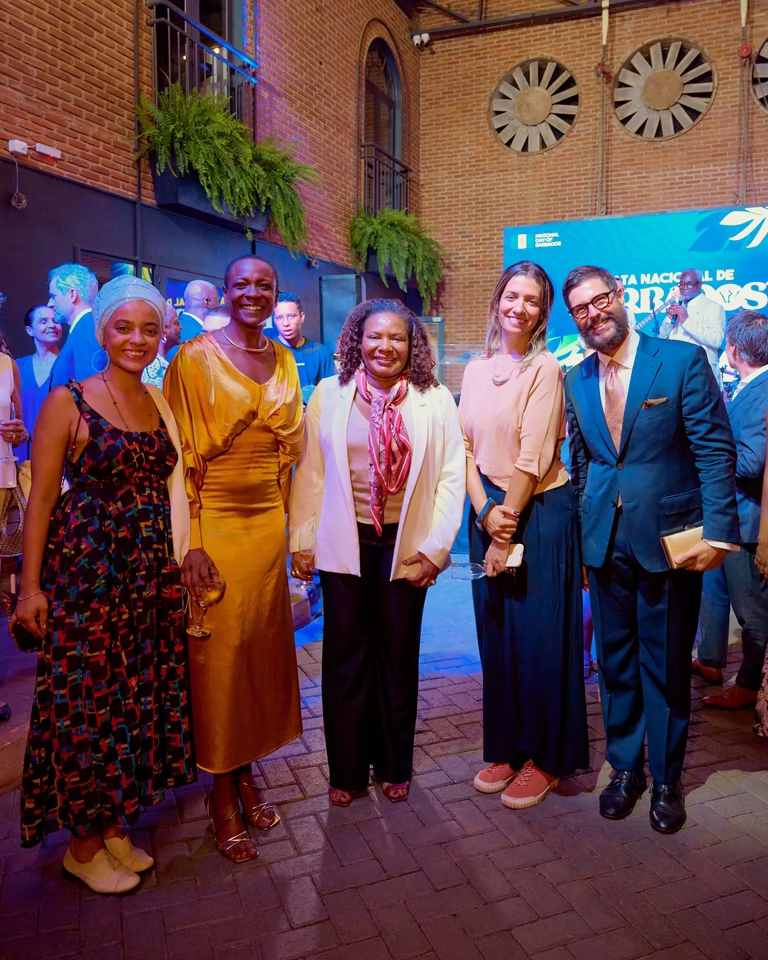 Convidados posam sorridentes no pátio de tijolos durante a recepção do summit