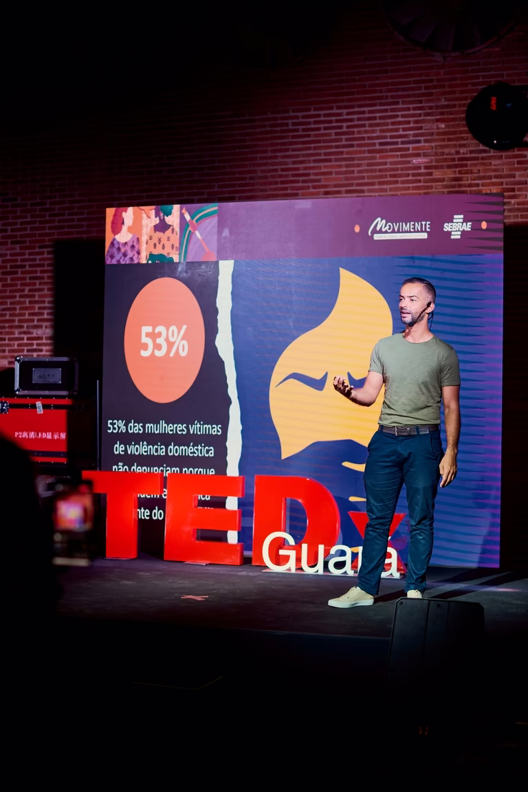 Palestrante apresenta dados no telão durante palestra do TEDx Guará