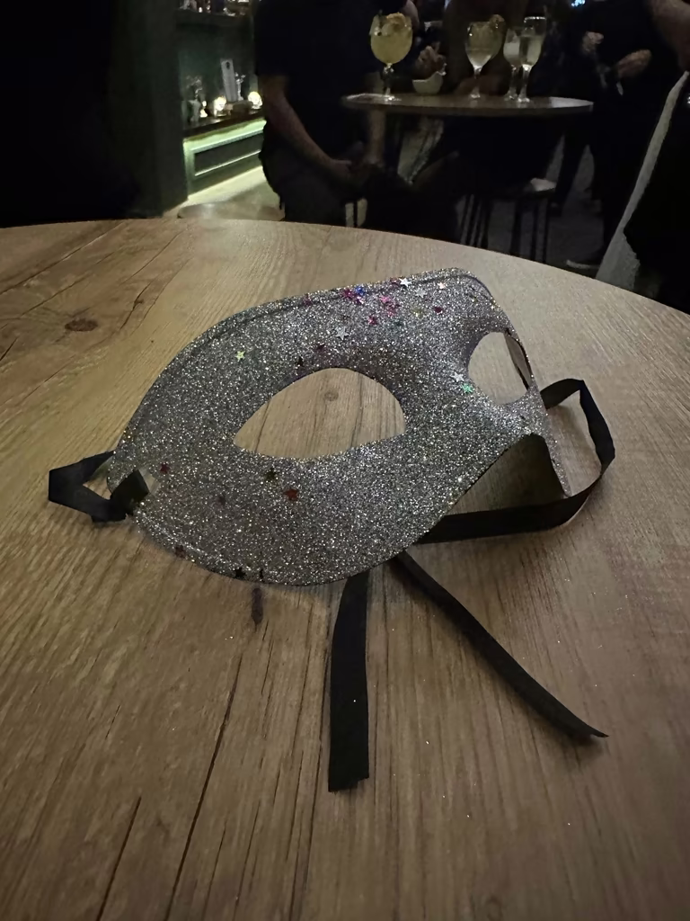Máscara prateada com glitter sobre mesa de madeira durante o evento
