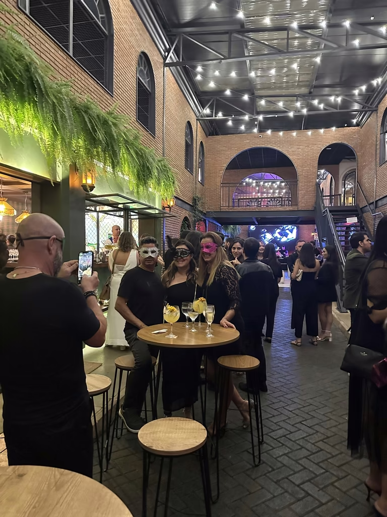 Convidados mascarados em pátio de tijolos com luzes de festa no Top Decor